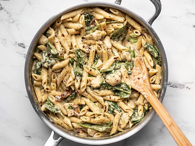 This super lush and Creamy Pesto Chicken Pasta is perfect for busy weeknights. Everything cooks in one pot and is done in under 30 minutes! BudgetBytes.com Finished creamy pesto chicken pasta in the skillet topped with black pepper and crushed red pepper