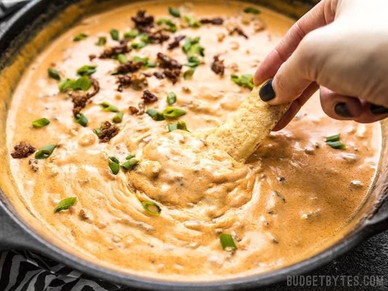 This incredibly easy Spicy Chorizo Cheese Dip only has five ingredients, no processed cheese, and is sure to be the star of your next party! Budgetbytes.com Close up of a chip being dipped into Spicy Chorizo Cheese Dip